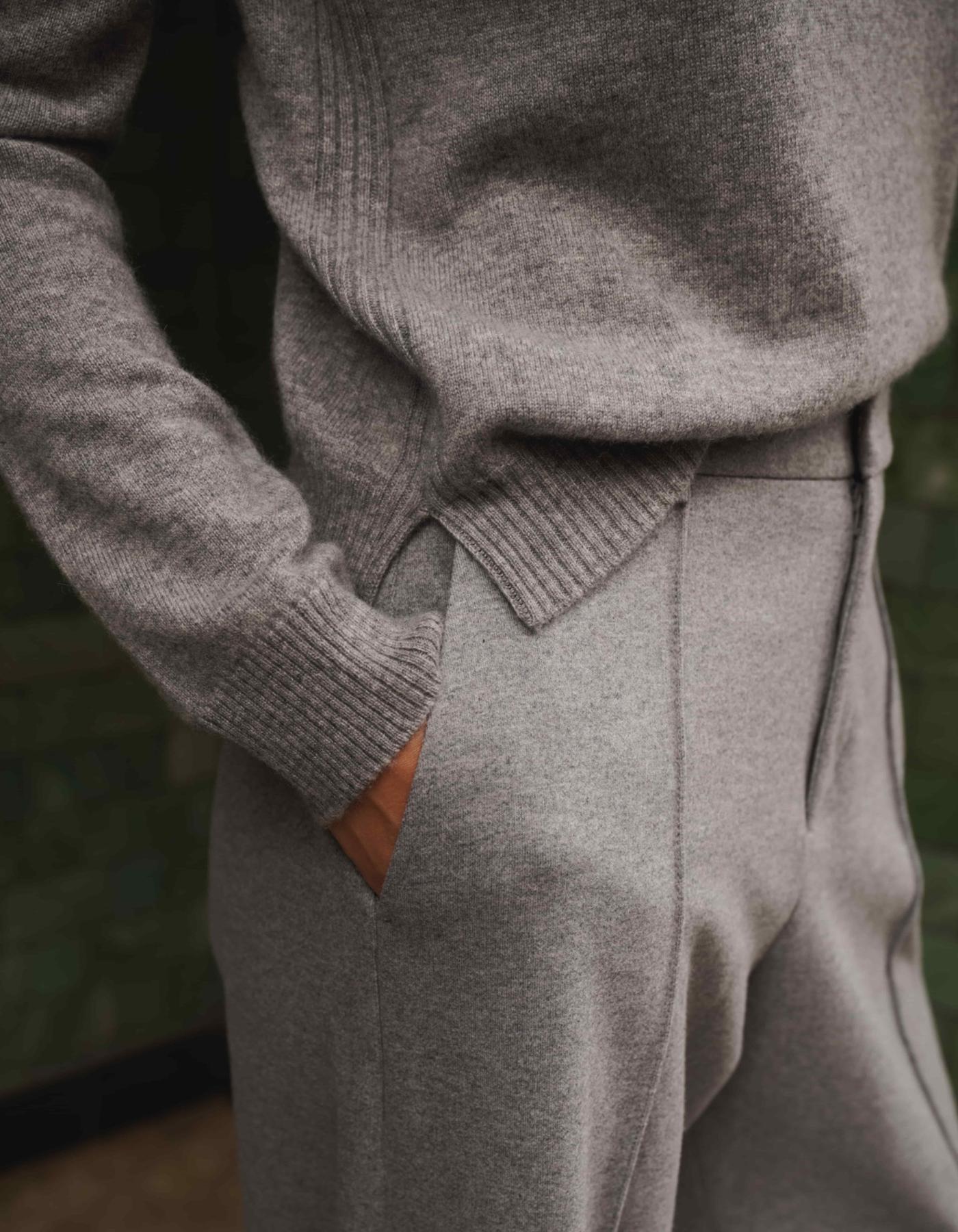 Person wearing a gray sweater and pants with a blurred background
