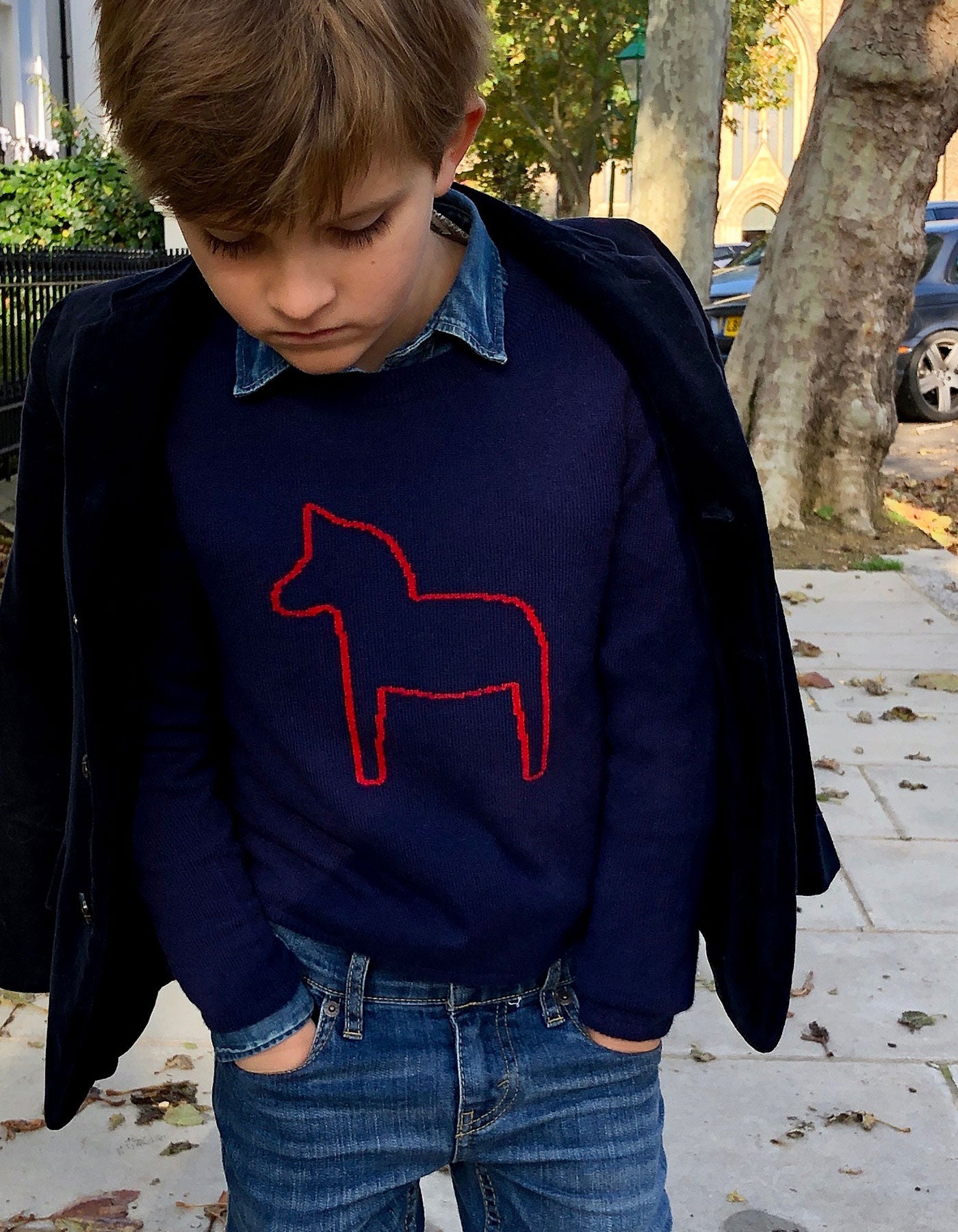 Boy wearing childrens cashmere, a malin darlin Little Pony navy cashmere jumper, under a jacket.