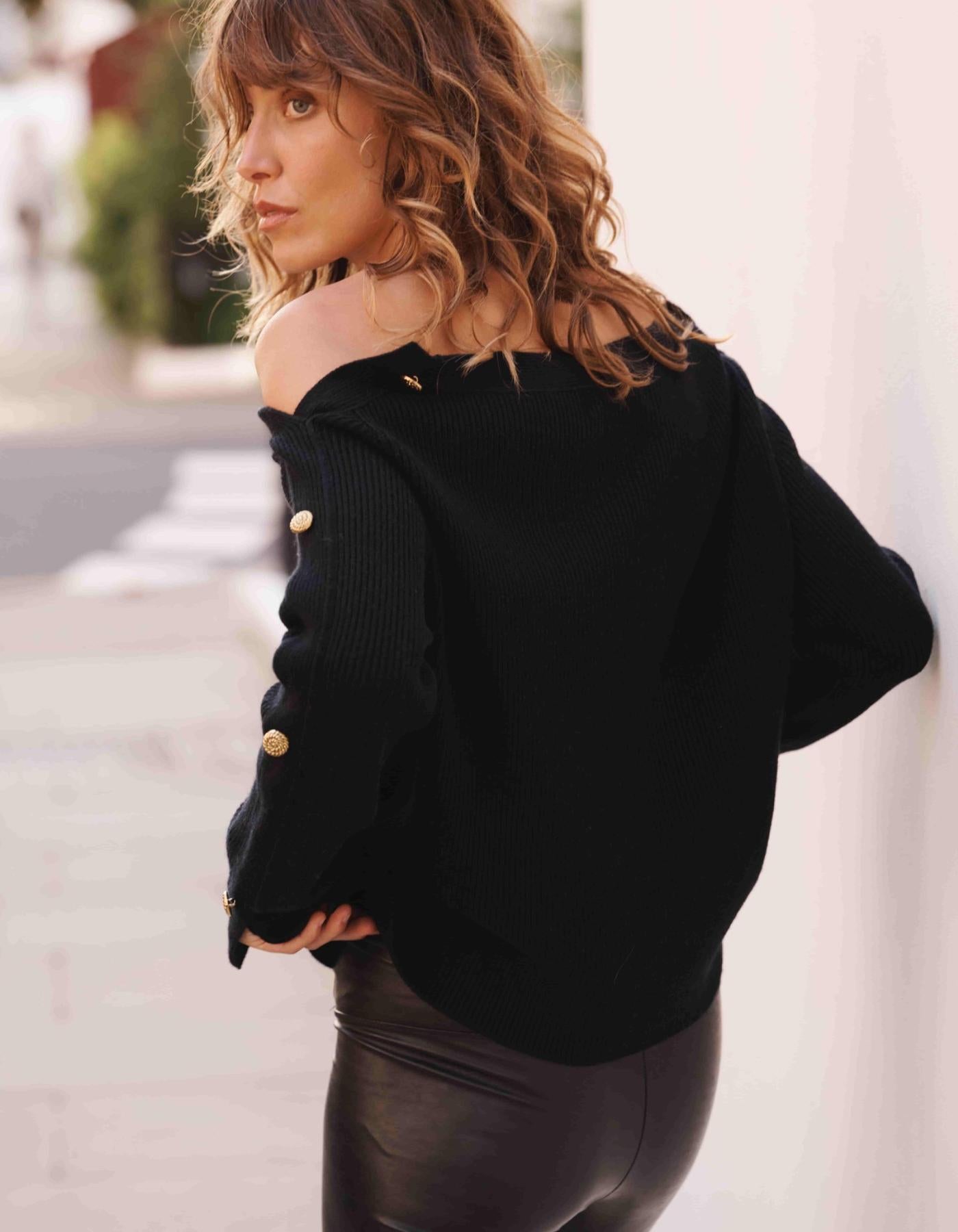Woman wearing a black cashmere jumper with gold buttons in the street