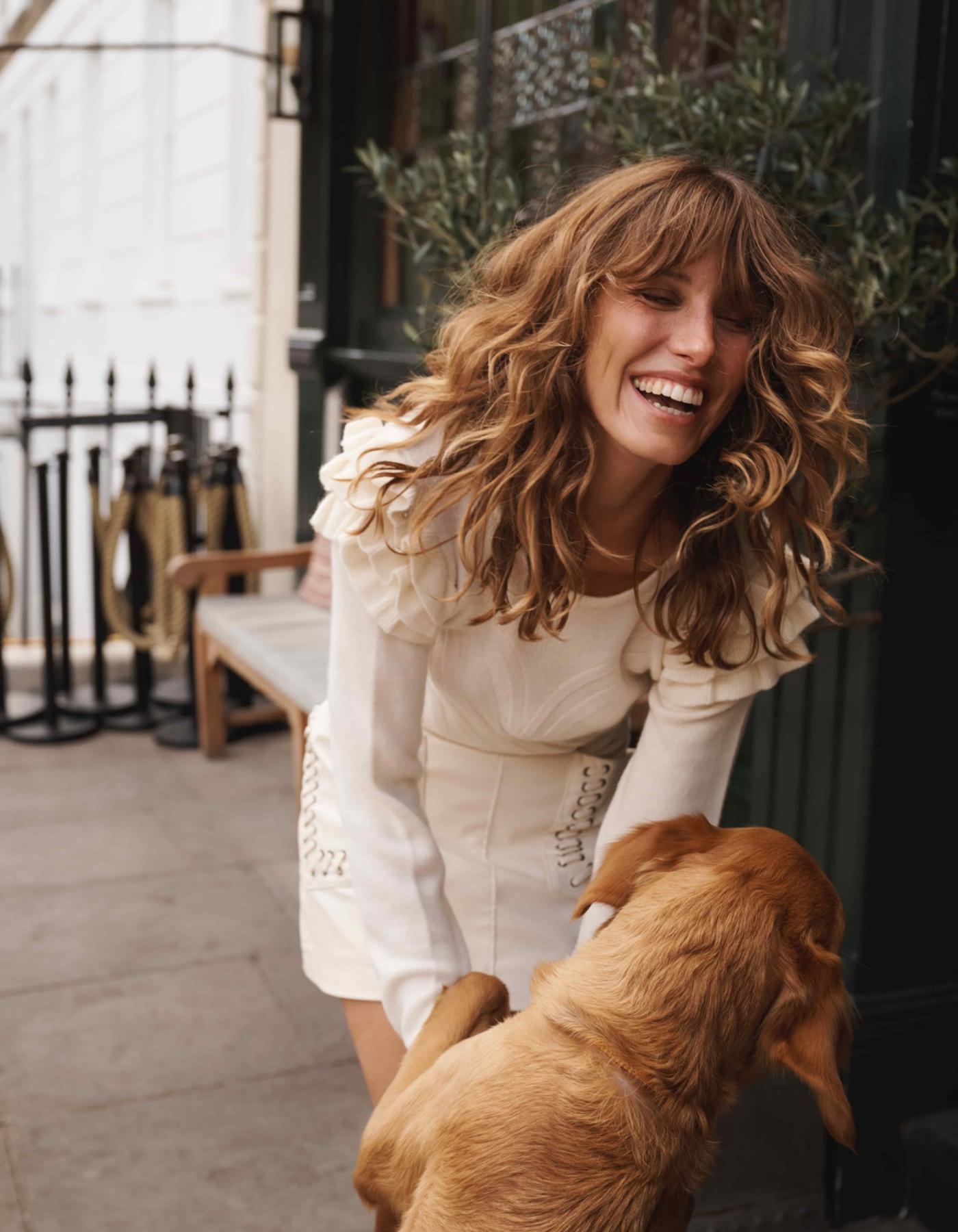 Woman with dog wearing cream cashmere jumper with ruffled shoulders