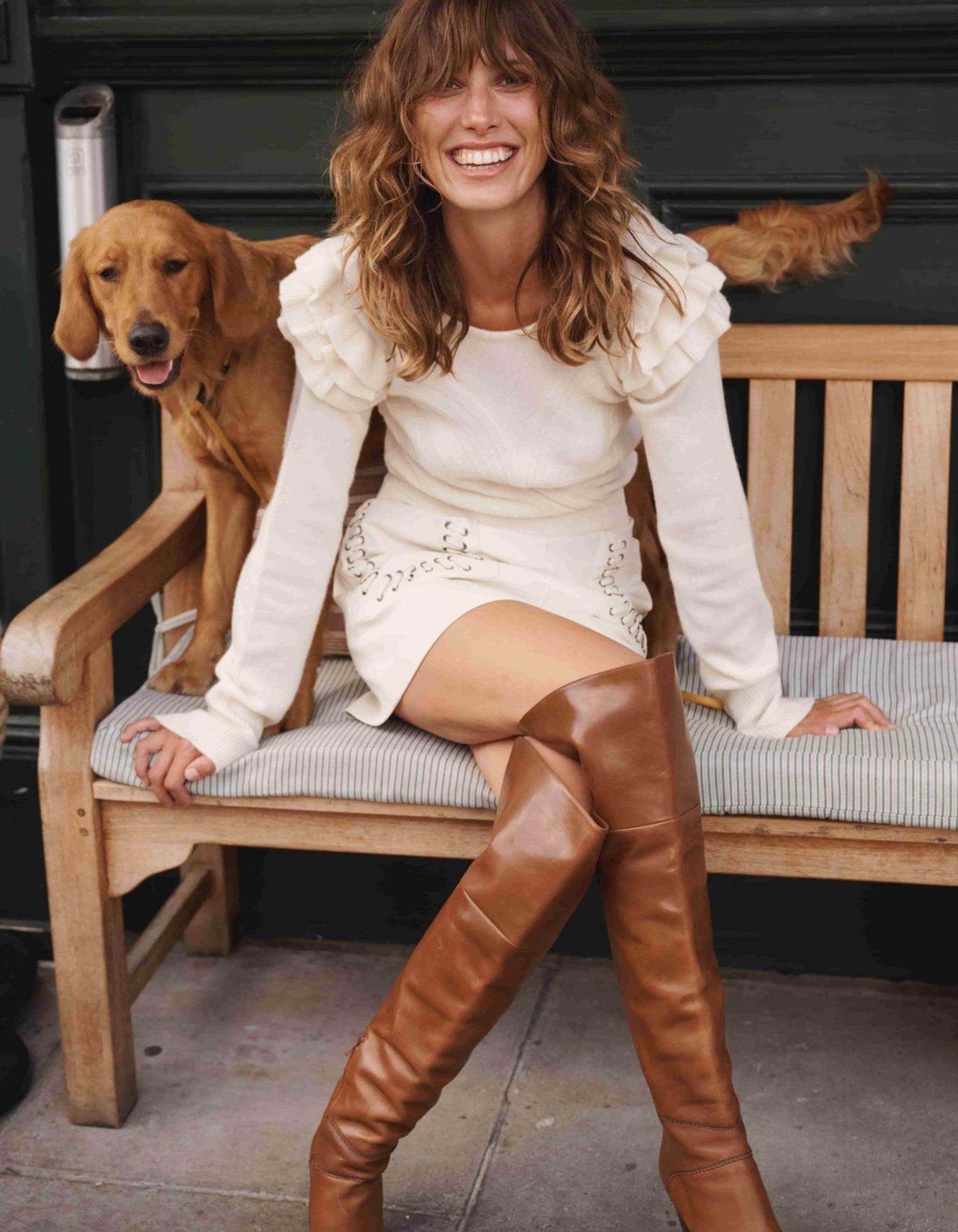 Woman with dog wearing cream cashmere jumper with ruffled shoulders and brown boots