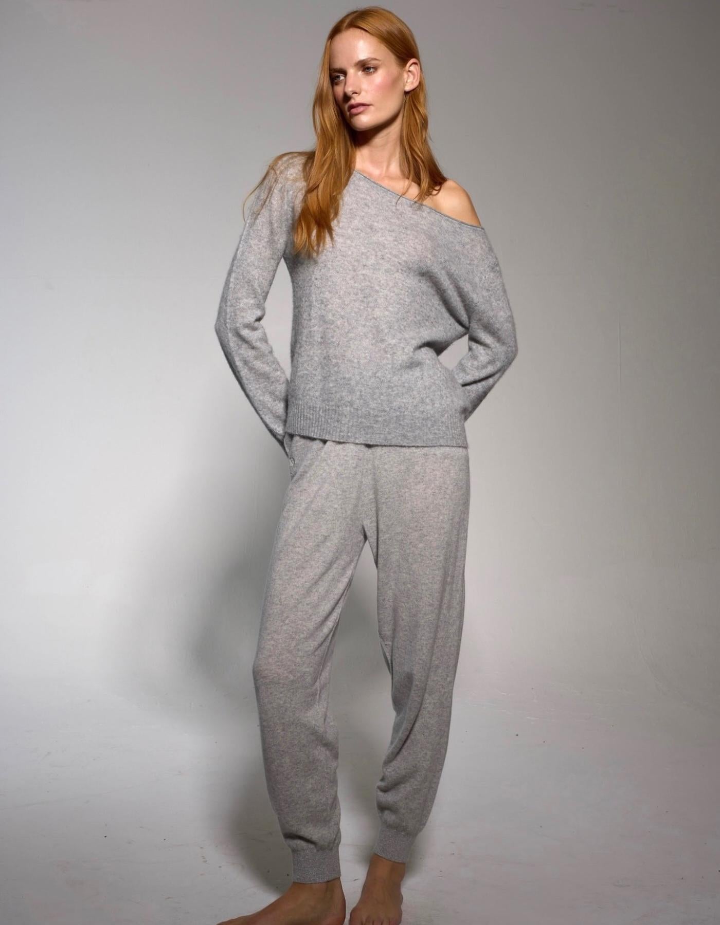 Woman wearing grey cashmere joggers on plain background 