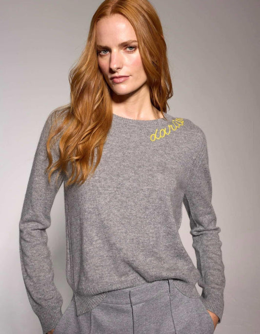 Woman wearing a grey sweater with 'Darlin' branding on a plain background