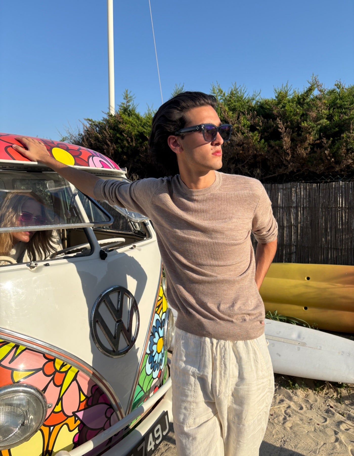 Man standing next to a colorful Volkswagen van on a beach
