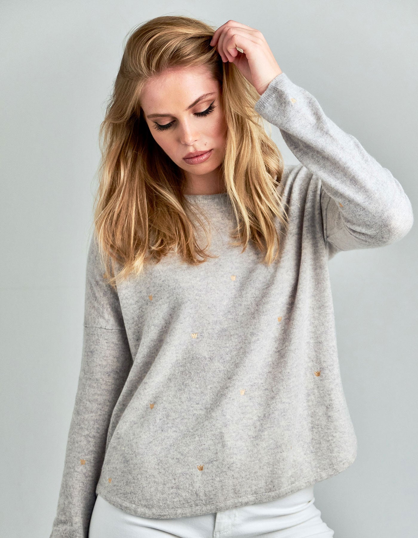 Studio picture of a model wearing a malin darlin Hundred Crowns cashmere jumper in grey marl colourway.
