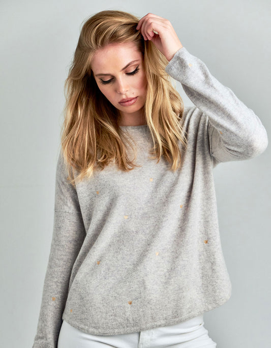 Studio picture of a model wearing a malin darlin Hundred Crowns cashmere jumper in grey marl colourway.