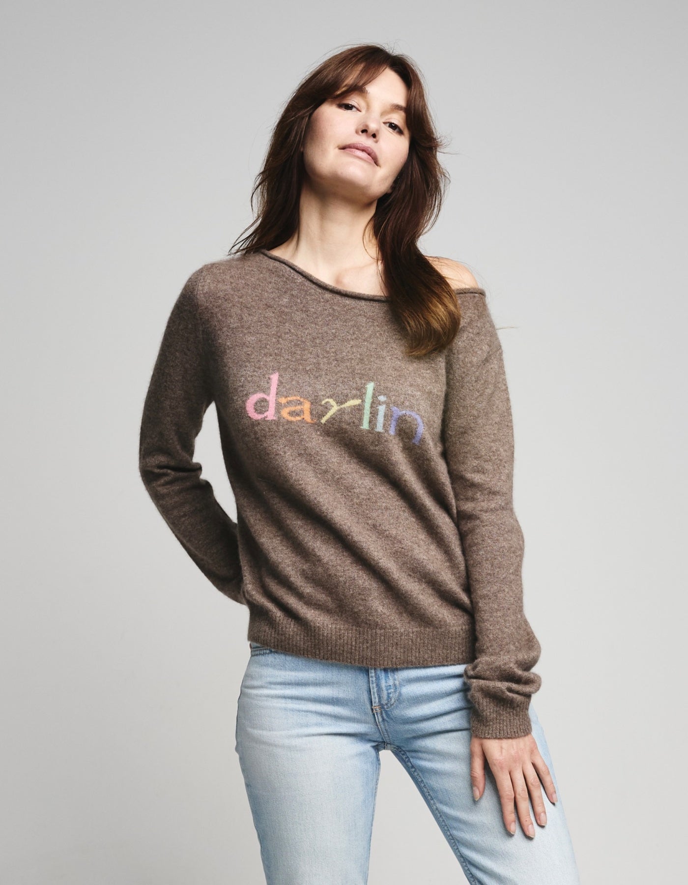 Woman wearing a beige cashmere sweater with 'darlin' text on a gray background