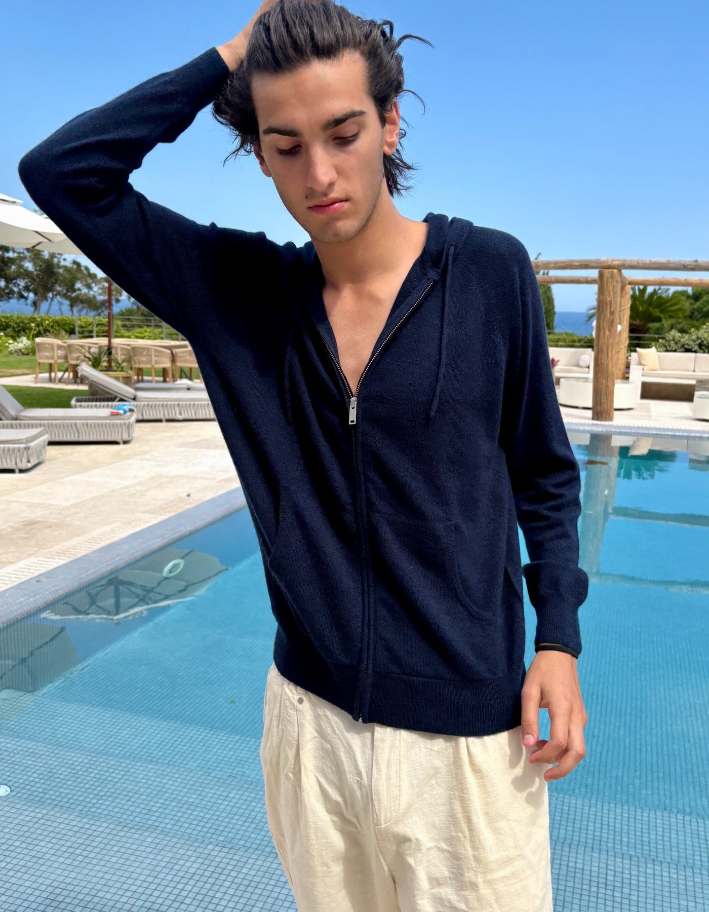 Man wearing a navy blue hoodie by a poolside