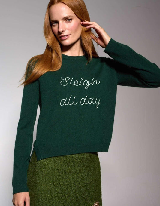 Woman wearing a green sweater with 'Sleigh all day' text on a plain background