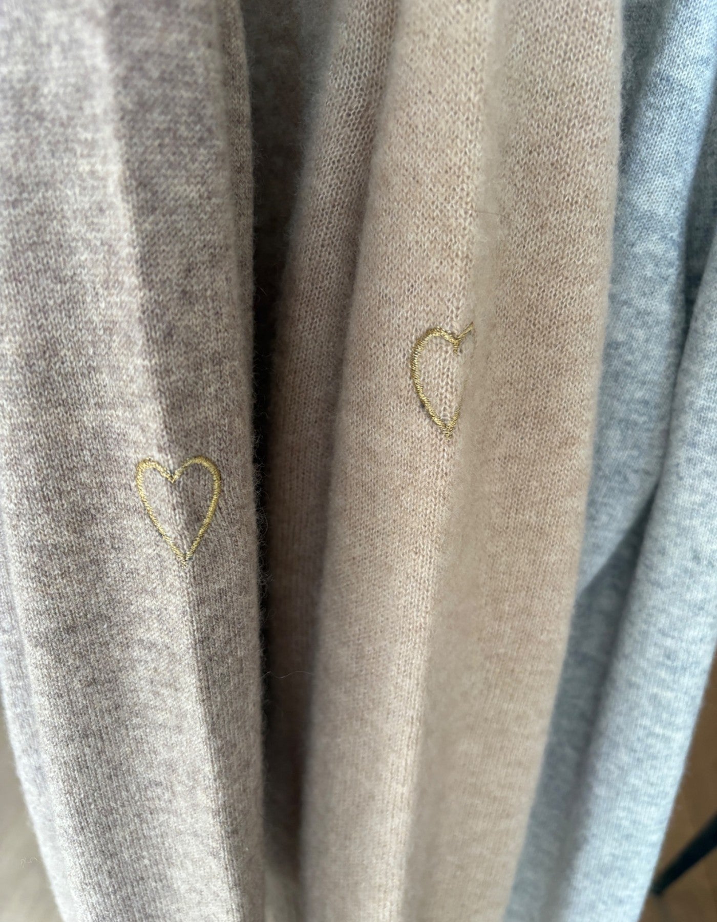 Close-up of cashmere with embroidered hearts in various colors.